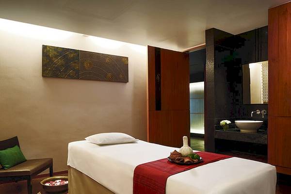 Massageraum im JC Kevin Sathorn Bangkok Hotel mit weißem Bett und roter Decke.