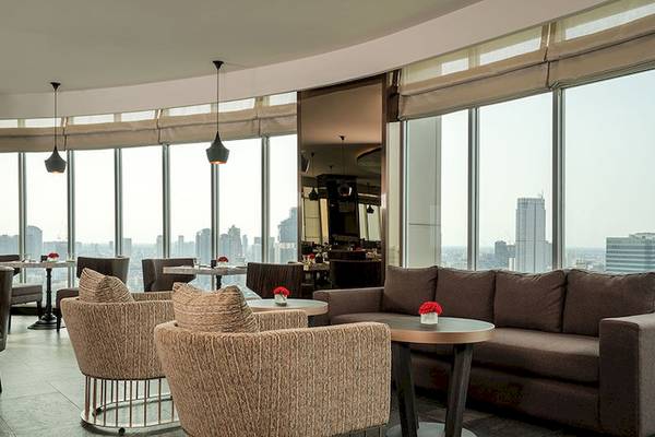 Innenraumansicht des JC Kevin Sathorn Bangkok Hotels mit großen Fenstern, die eine Stadtlandschaft zeigen.