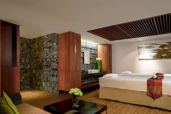 Schlafzimmer im JC Kevin Sathorn Bangkok Hotel mit zwei Betten, Holzboden und einer Steinwand.