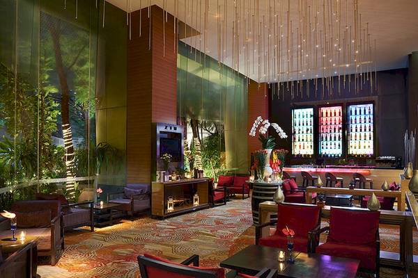 Loungebereich des JC Kevin Sathorn Bangkok Hotels mit tropischen Elementen und rotem Interieur.