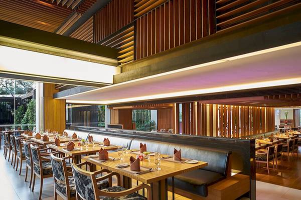 Innenansicht des JC Kevin Sathorn Bangkok Restaurants mit gedeckten Tischen und dekorativen Holzelementen.