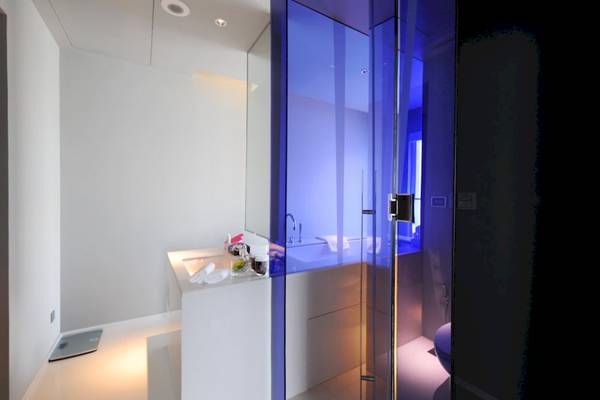 Modernes Badezimmer des Mode Sathorn Hotels mit Glaswand und blauer Beleuchtung.