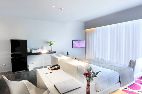 Innenansicht des Mode Sathorn Hotels, mit einem weißen Bett, Schreibtisch und modernem Dekor.