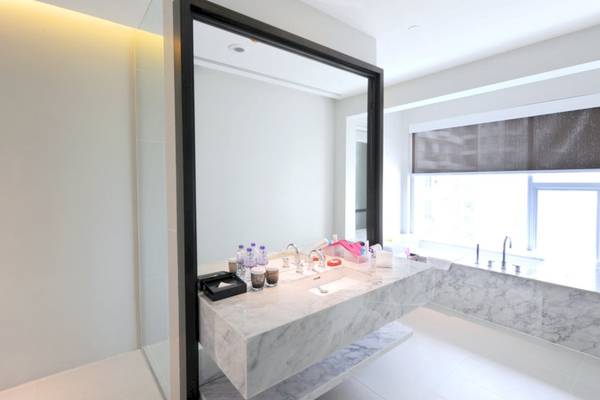 Das Badezimmer des Mode Sathorn Hotels mit einem großen Spiegel, Waschbecken und Badewanne.