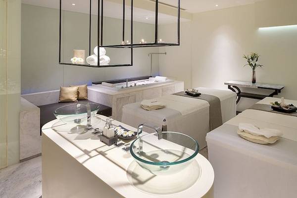 Spa-Behandlungsraum im Mode Sathorn Hotel mit drei Behandlungstischen, Badewanne, Vasen und Lampen.