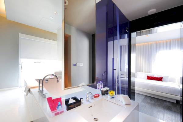 Das Badezimmer des Mode Sathorn Hotels mit einer Badewanne, Waschbecken und einem Bett im Hintergrund.