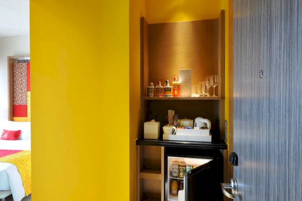 Ein Zimmer im Mode Sathorn Hotel mit einem Minikühlschrank, gefüllt mit Getränken und Snacks.