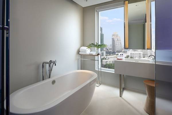 Badezimmer im Mode Sathorn Hotel mit Badewanne, Waschbecken und großer Fensteransicht