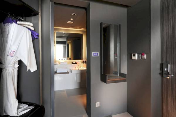 Innenansicht eines Mode Sathorn Hotelzimmers mit Robe, Badezimmer und Spiegel.