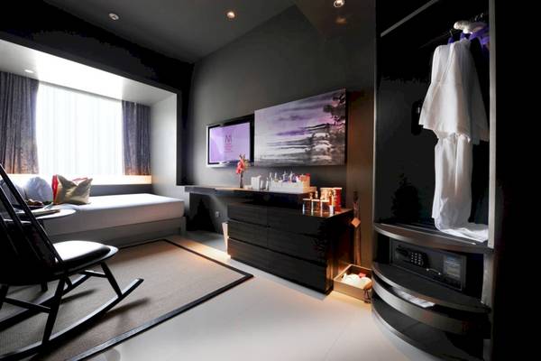 Innenansicht eines Mode Sathorn Hotelzimmers mit Bett, Fernseher, Schrank und Dekor.