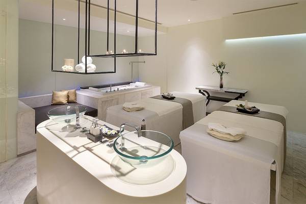 Spa-Behandlungsraum im Mode Sathorn Hotel mit Badewanne, Sesseln und Pflanzen.