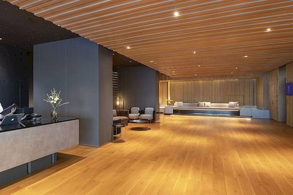 Empfangsbereich des Mode Sathorn Hotels mit Rezeptionstresen, Frau am Laptop, Holzboden und modernen Möbeln.