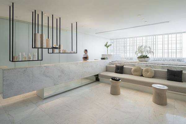 Empfangsbereich des Mode Sathorn Hotels mit weißem Marmortresen und Sitzbereich.