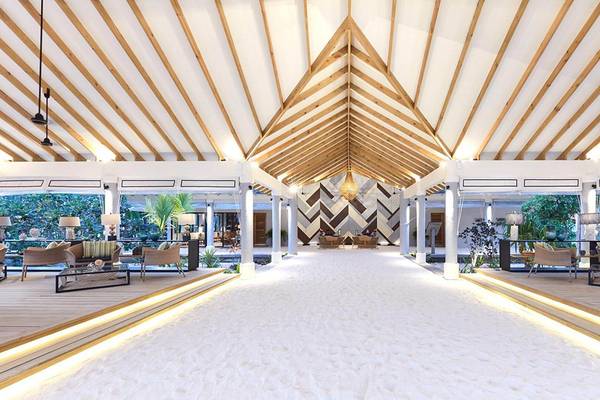 Hotellobby des Amari Havodda Maldives mit weißem Sandboden und Holzdecken.