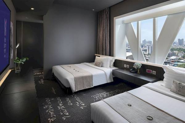 Innenansicht eines Zimmers im Mode Sathorn Hotel mit zwei Betten und Blick auf die Stadt.