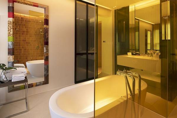 Ein Badezimmer im Mode Sathorn Hotel mit Badewanne, Spiegel und hellen Fliesen.
