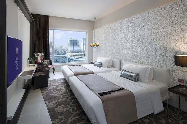 Schlafzimmer im Mode Sathorn Hotel mit zwei Betten und Blick auf die Stadt.