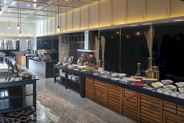Speisesaal des Mode Sathorn Hotels mit Buffet und Köchen, die Speisen zubereiten.