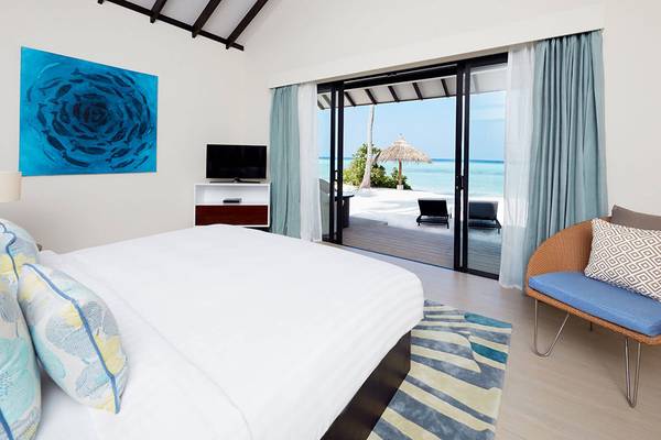 Schlafzimmer im Amari Havodda Maldives Hotel mit Blick auf den Strand und das Meer.