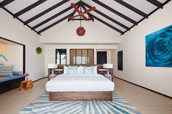 Schlafzimmer im Amari Havodda Maldives mit großem Bett, Dekor und Deckenventilator.