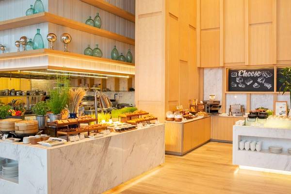 Frühstücksbuffet im AVANI+ Riverside Bangkok mit verschiedenen Gerichten und Utensilien.