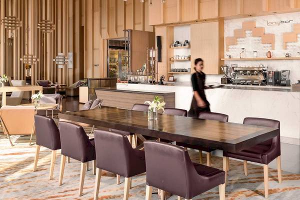 AVANI+ Riverside Bangkok Hotel Innenraum mit Esstisch, Stühlen und Bar.