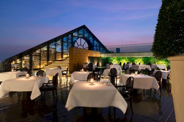 Dachrestaurant des Tower Club At Lebua bei Nacht mit beleuchteten Tischen und Stühlen.