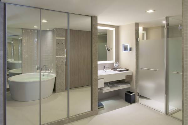 Ein modernes Badezimmer des Novotel Bangkok Sukhumvit 20 Hotel mit Badewanne, Spiegel, Waschbecken und Dusche.