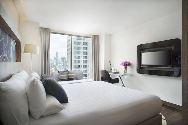 Innenansicht eines Hotelzimmers im Novotel Bangkok Sukhumvit 20 mit Bett, Fernseher und Stadtblick.