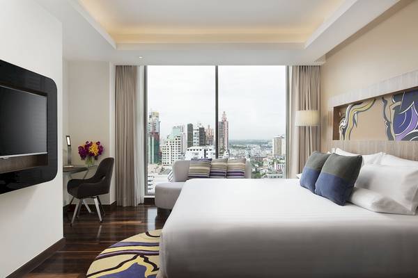 Suite-Zimmer im Novotel Bangkok mit Bett, Schreibtisch und Blick auf die Stadt.
