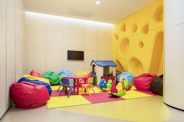 Ein Kinderspielzimmer mit gelben Wänden, die wie Käse aussehen, bunten Beanbags und Spielzeug.