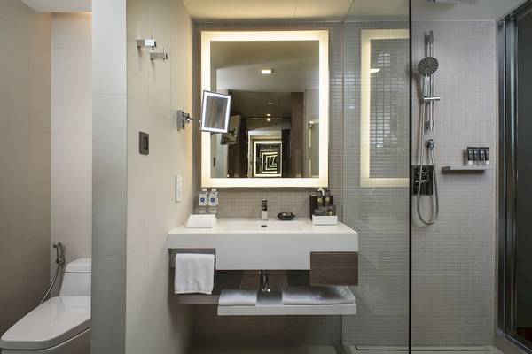 Badezimmer im Novotel Bangkok Sukhumvit 20 Hotel mit großem Spiegel, Waschbecken und Dusche.