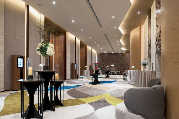 Hotellobby des Novotel Bangkok Sukhumvit 20 mit runden Tischen, Blumenarrangements und modernen Möbeln.