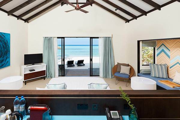 Innenansicht eines Zimmers im Amari Havodda Maldives mit einem Bett, Fernseher, und Meerblick.
