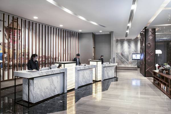 Hotelrezeption im Novotel Bangkok Sukhumvit 20 mit Marmortischen und moderner Architektur.