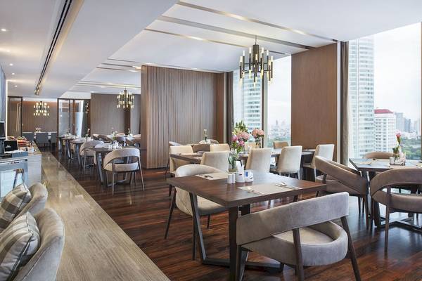 Innenansicht des Restaurants im Novotel Bangkok Sukhumvit 20 mit modernen Möbeln und blumigen Dekorationen.