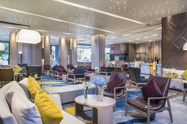 Hotellobby des Novotel Bangkok Sukhumvit 20 mit modernen Möbeln und blauem Teppich.