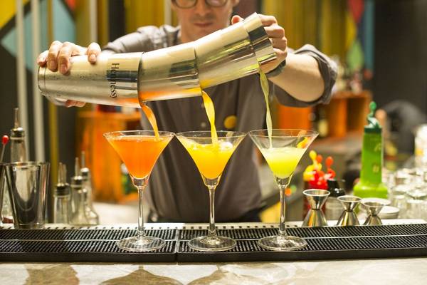 Ein Barkeeper gießt Cocktails in Martini-Gläser auf einer Bar-Theke.