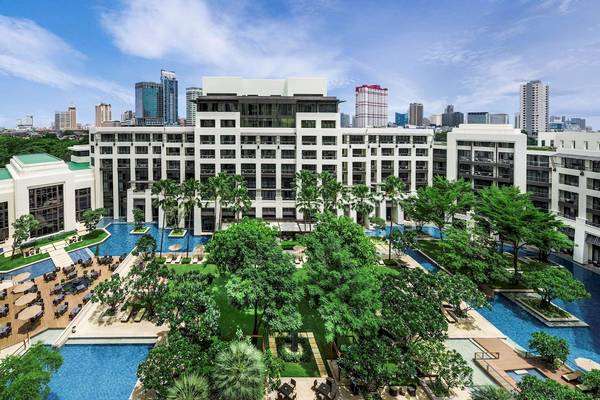 Außenansicht des Siam Kempinski Hotel Bangkok mit Swimmingpool und grünen Bäumen