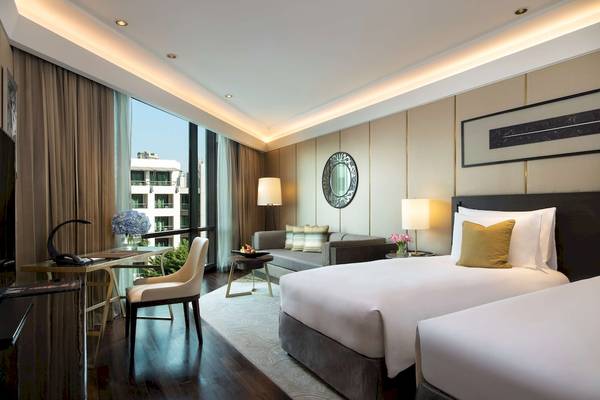 Innenansicht der Suite im Siam Kempinski Hotel Bangkok mit zwei Betten, Schreibtisch und Sofa.