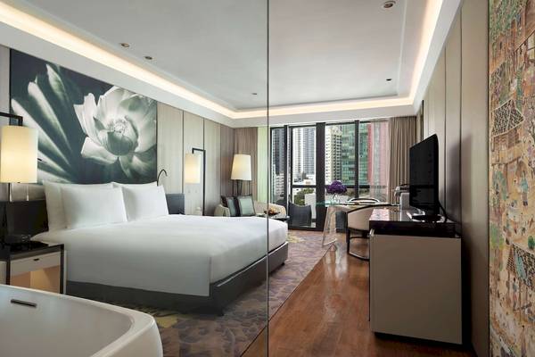 Ein elegantes Schlafzimmer im Siam Kempinski Hotel Bangkok mit Bett, Schreibtisch und Fernseher.