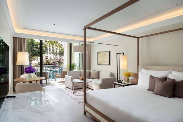Innenansicht einer Suite im Siam Kempinski Hotel Bangkok mit Bett, Sofa und Tisch.