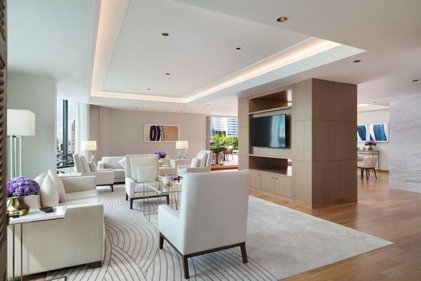 Wohnzimmer im Siam Kempinski Hotel Bangkok mit weißen Möbeln, Holzboden und zentralem Fernseher.