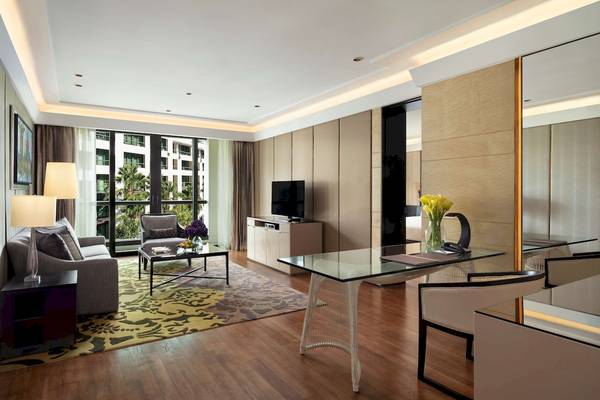 Wohnzimmer des Siam Kempinski Hotel Bangkok mit Fernseher, Sofa, Tisch und Glastisch.