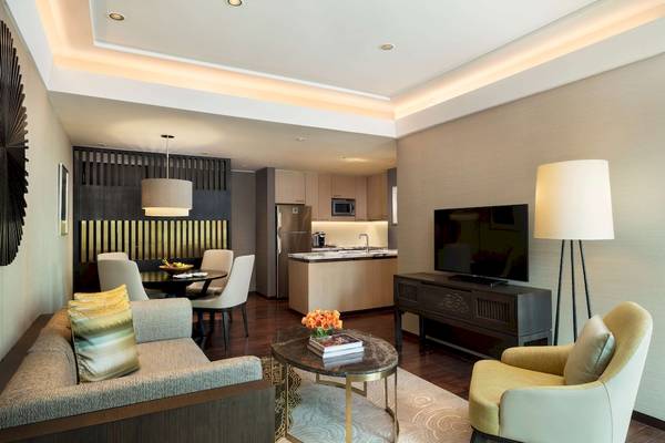 Wohnbereich im Siam Kempinski Hotel Bangkok mit Tisch, Sofa und Fernseher.