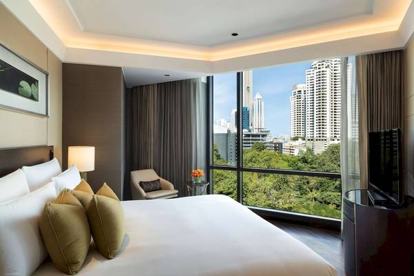 Ausblick aus dem Zimmer des Siam Kempinski Hotel Bangkok mit Bett, Fenstern und Stadtsicht.