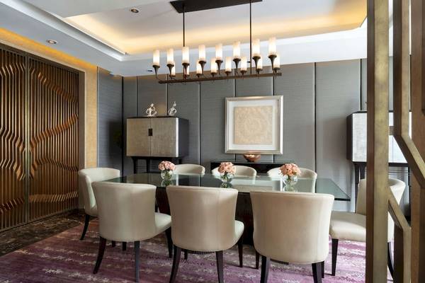Esszimmer im Siam Kempinski Hotel Bangkok mit Tisch, Stühlen und Blumenarrangements.