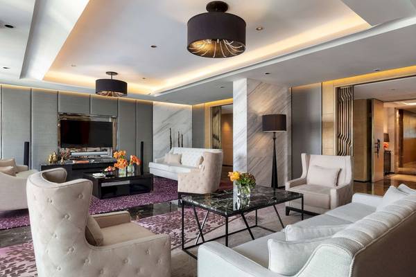 Wohnzimmer im Siam Kempinski Hotel Bangkok mit weißen Möbeln, einem Fernseher und Blumenvasen.