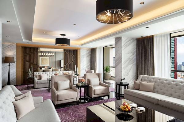 Wohnzimmer im Siam Kempinski Hotel Bangkok mit weißen Möbeln und einem großen Fenster.