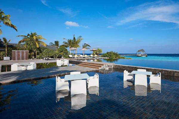 Außenpoolbereich des Amari Havodda Maldives mit weißen Tischen und Stühlen.